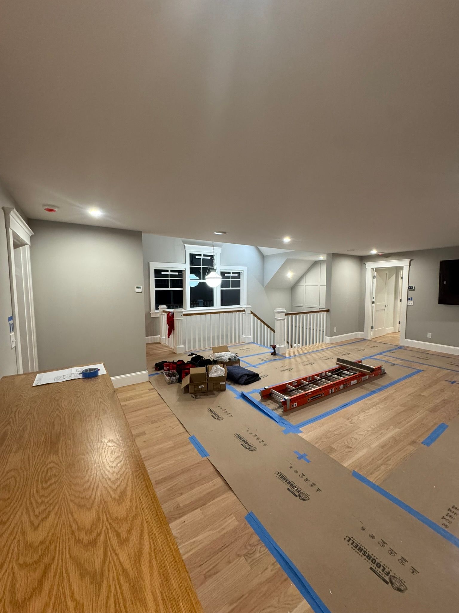 Interior room with wood floor, gray walls, white trim, and construction materials under renovation.