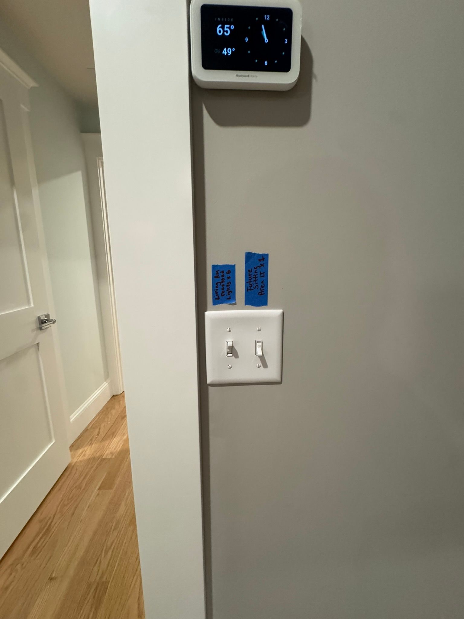 Hallway wall with thermostat, light switch, and two blue tape strips above the switch.
