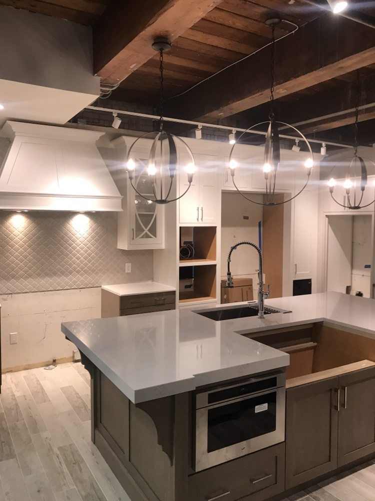 Modern kitchen with gray island, stainless appliances, pendant lights, and exposed wood ceiling