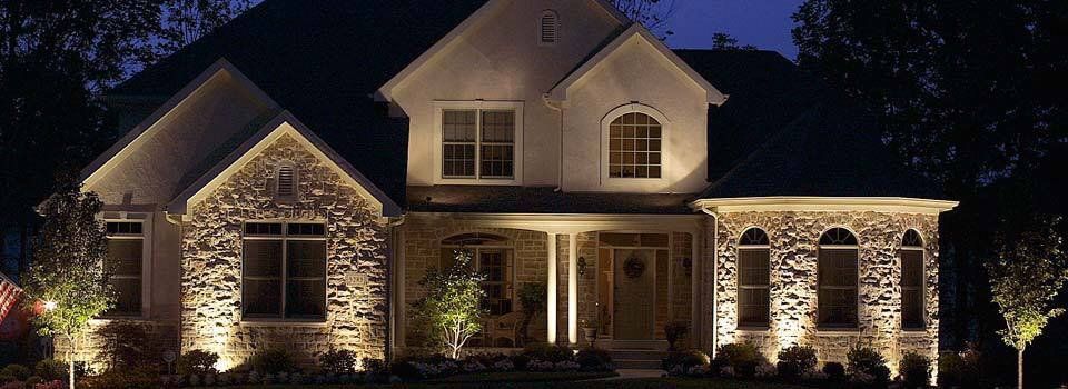 Illuminated stone house at night with warm exterior lights and a front porch