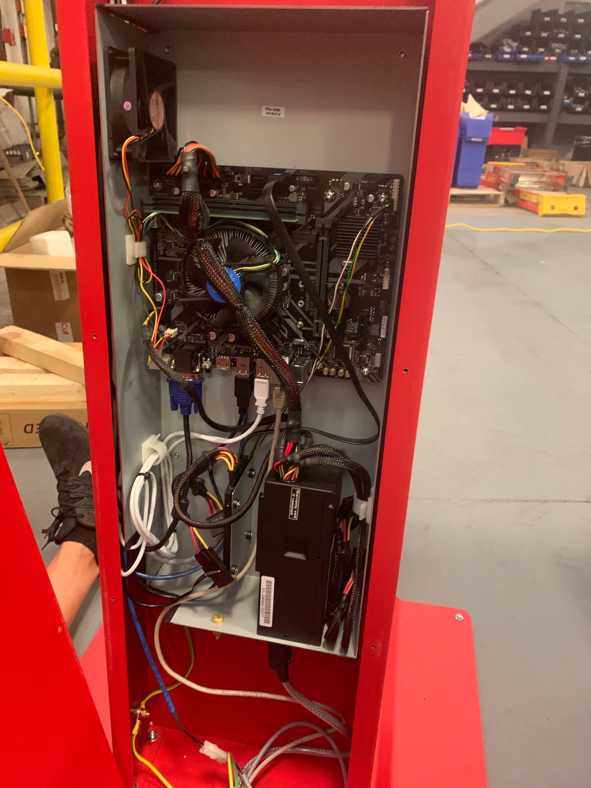 Open red equipment cabinet with exposed wiring and electronics inside a workshop.