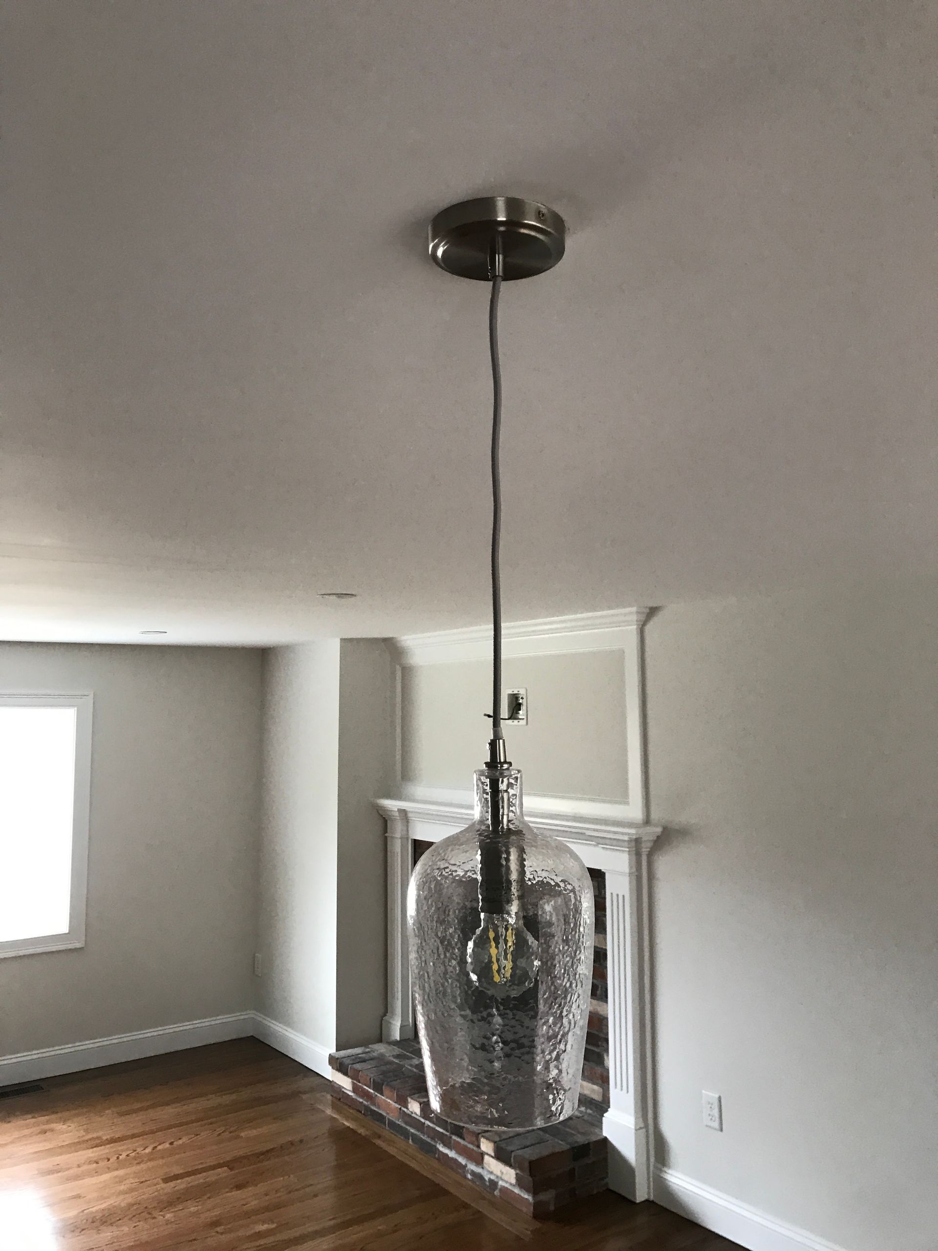 Living room with a hanging light fixture centered over a fireplace
