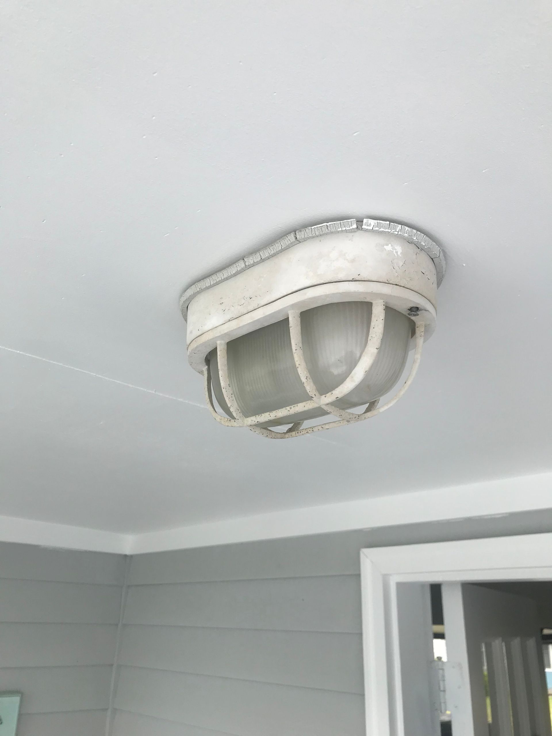 Close-up of a white outdoor ceiling light mounted on a porch ceiling.