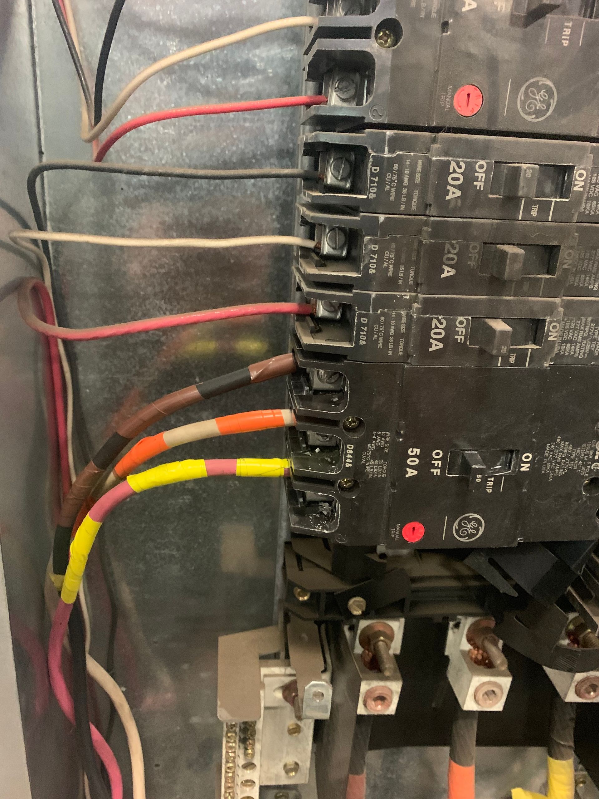 Close-up of electrical control panel wiring with red, yellow, black, and white wires on circuit breakers