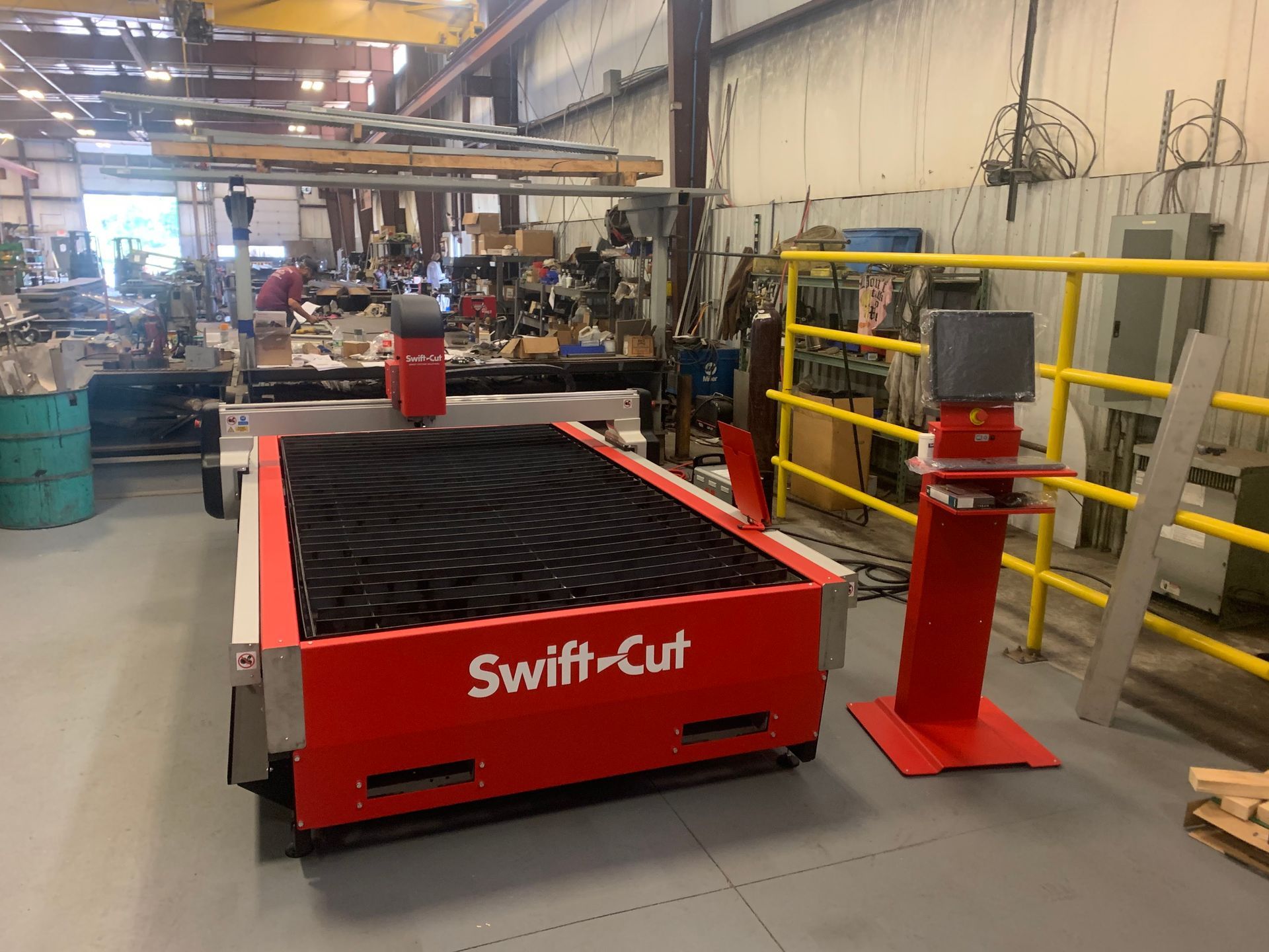 Red Swift-Cut industrial machine in a workshop next to yellow safety railings and a red post.
