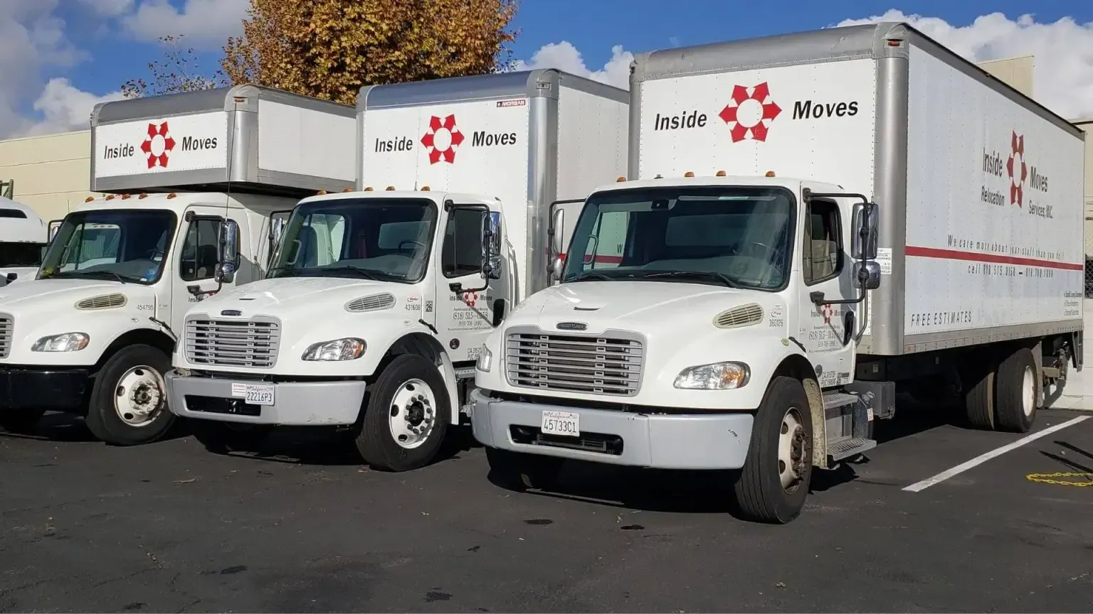 Three white moving trucks parked in a lot