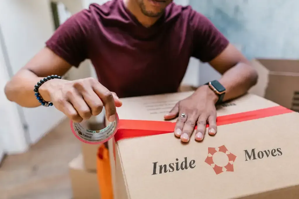 Person sealing a cardboard moving box with packing tape