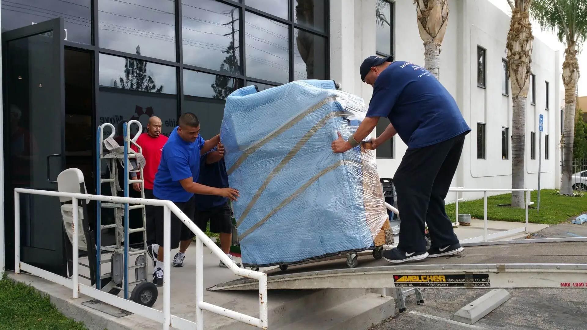 Workers unload a large wrapped package from a truck
