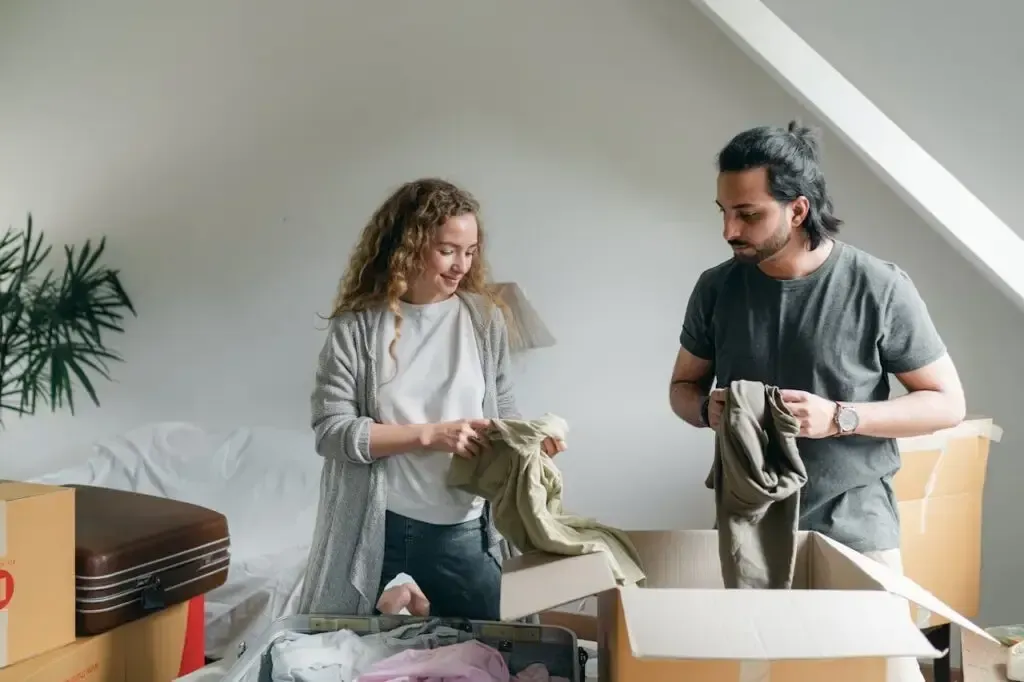 Two people unpacking clothes from boxes