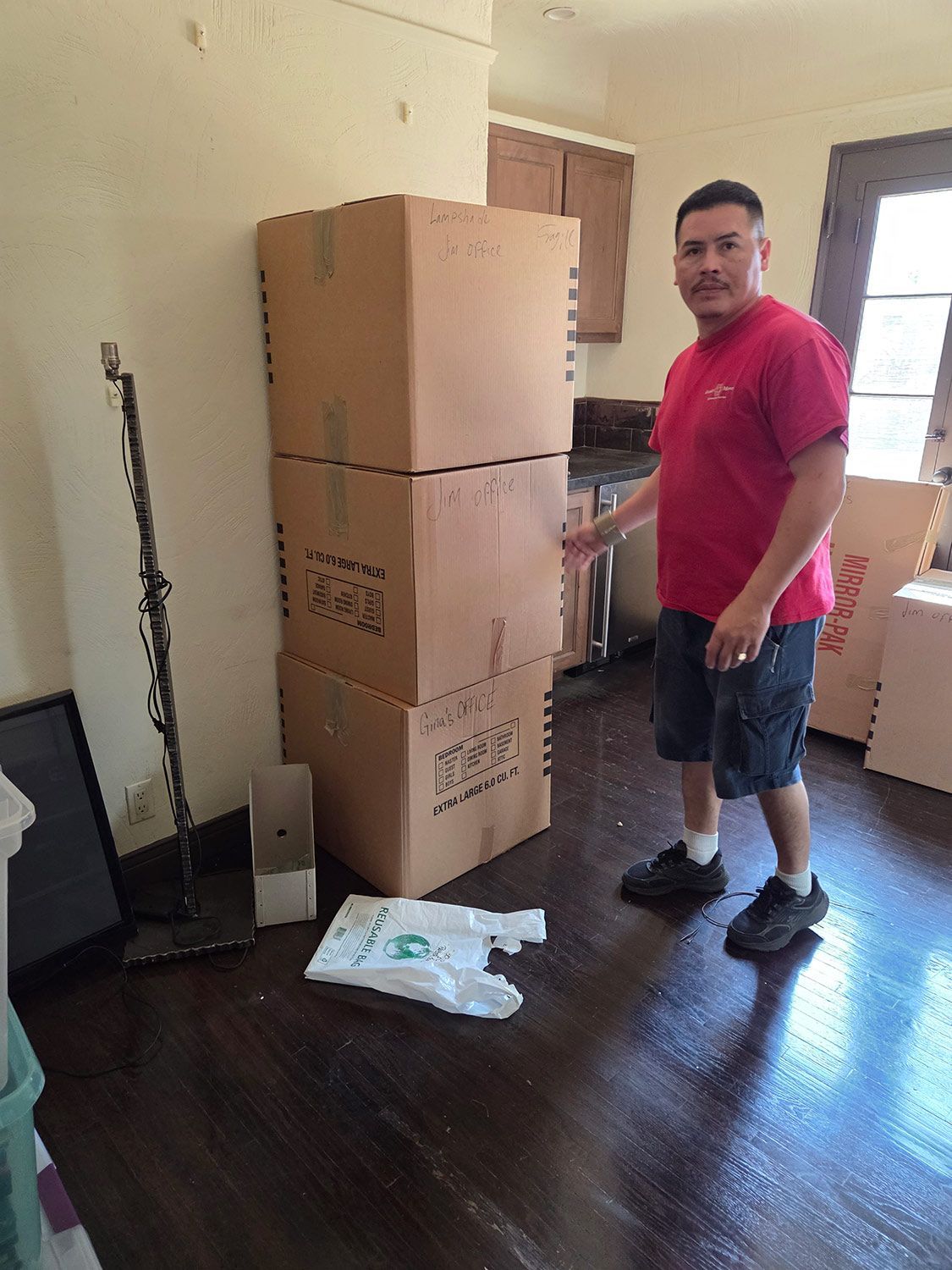 Man standing beside stacked cardboard boxes in a room