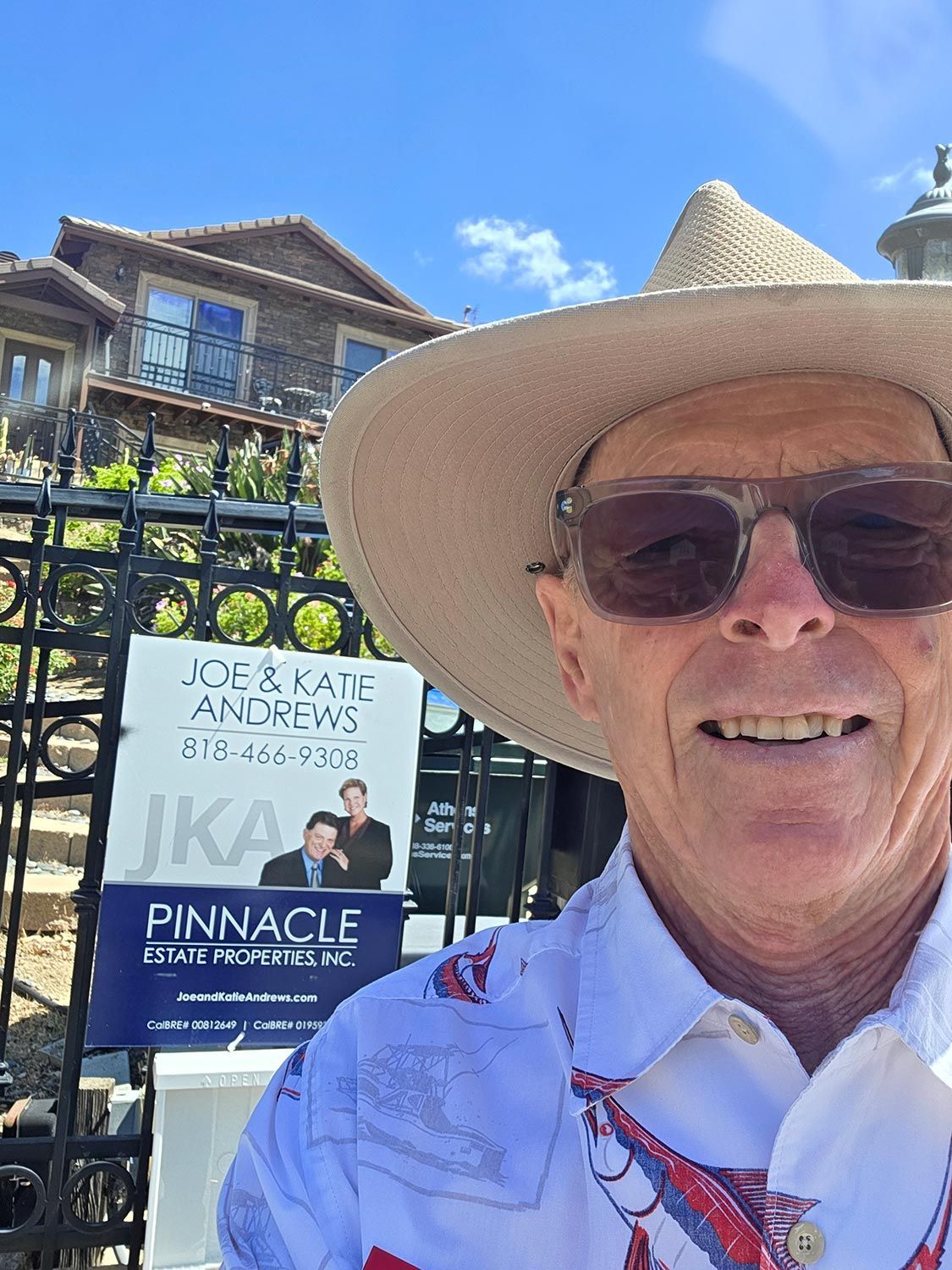 Man in a straw hat and sunglasses smiling in front of a Pinnacle sign