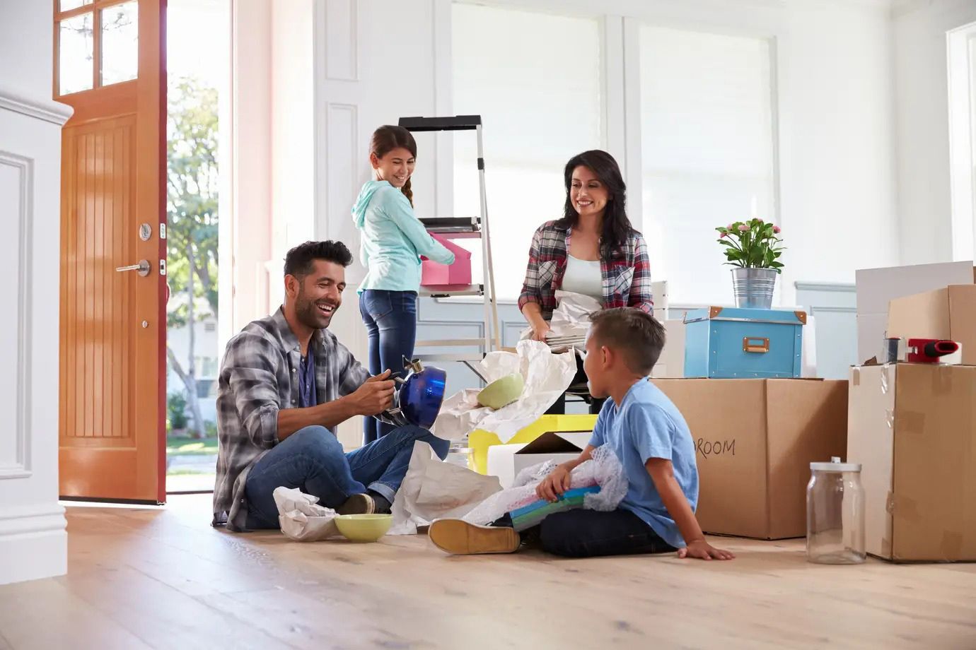 Family packing boxes and sorting toys in a bright living room