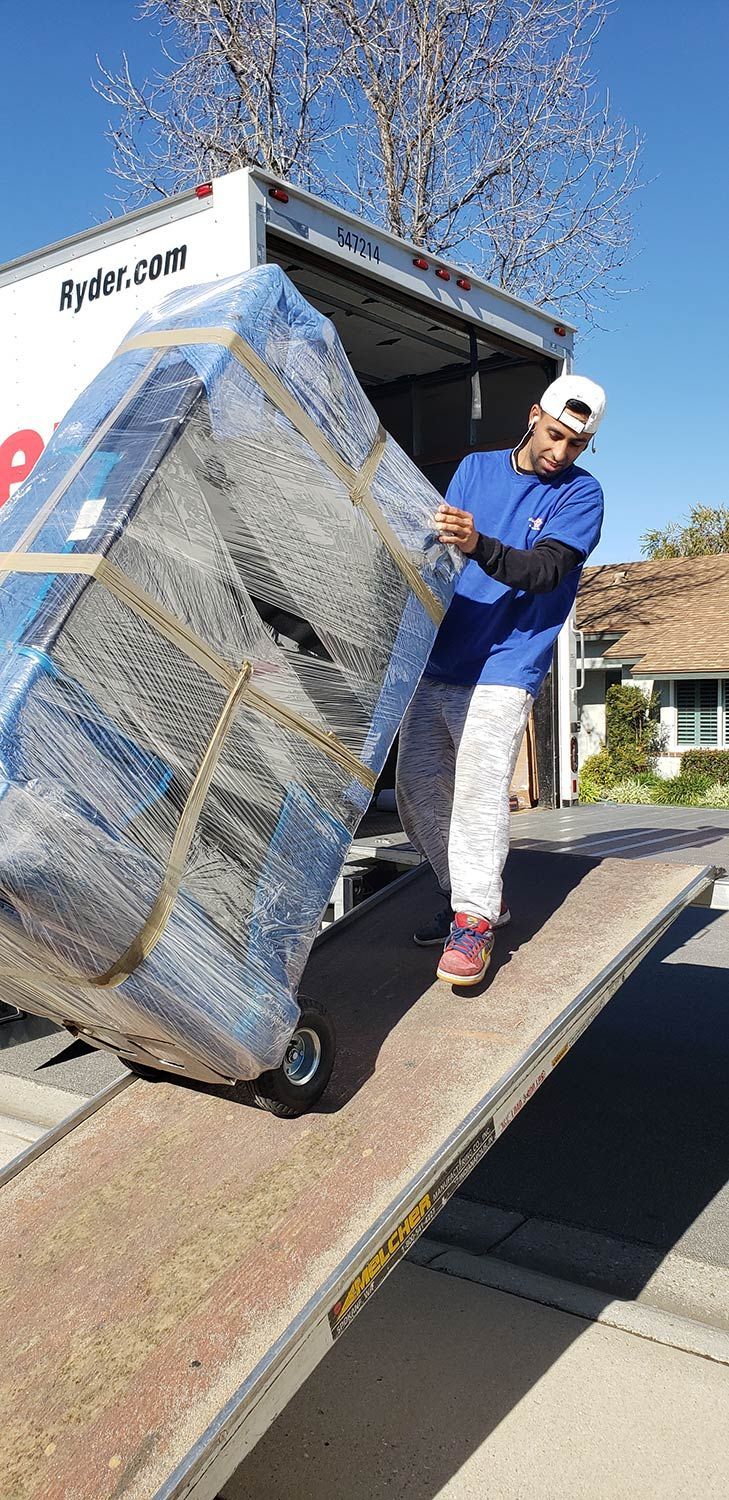 Worker loading a large wrapped mattress onto a truck