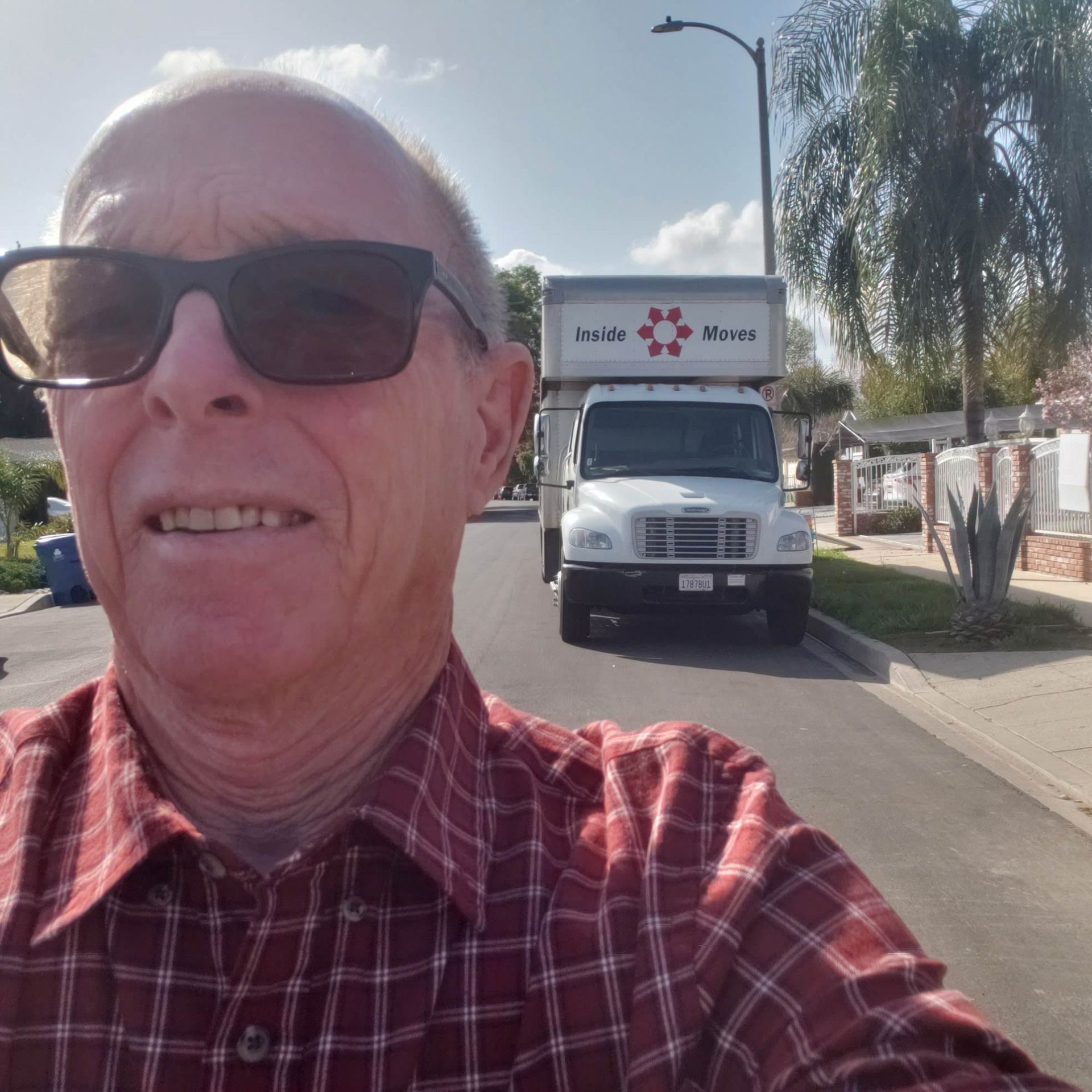 Man on a sunny street with moving  truck in the background