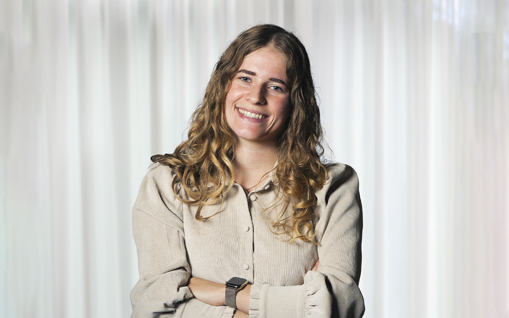 Vrouw die met gekruiste armen lachend in de camera kijkt