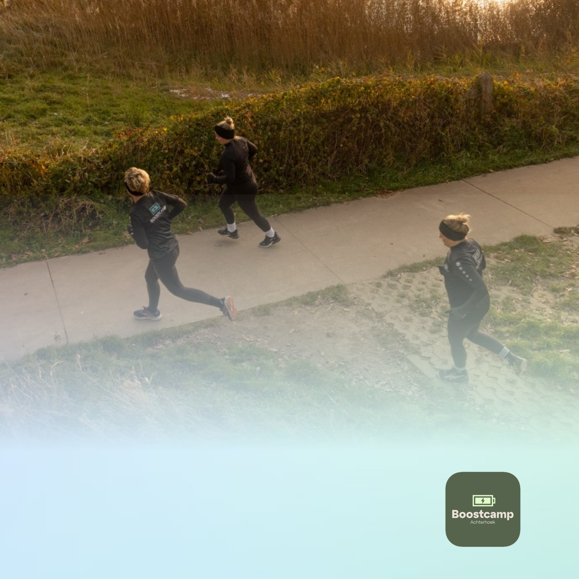 Drie mensen wandelen en rennen op een landweggetje langs hoog gras, met fel zonlicht op de voorgrond.
