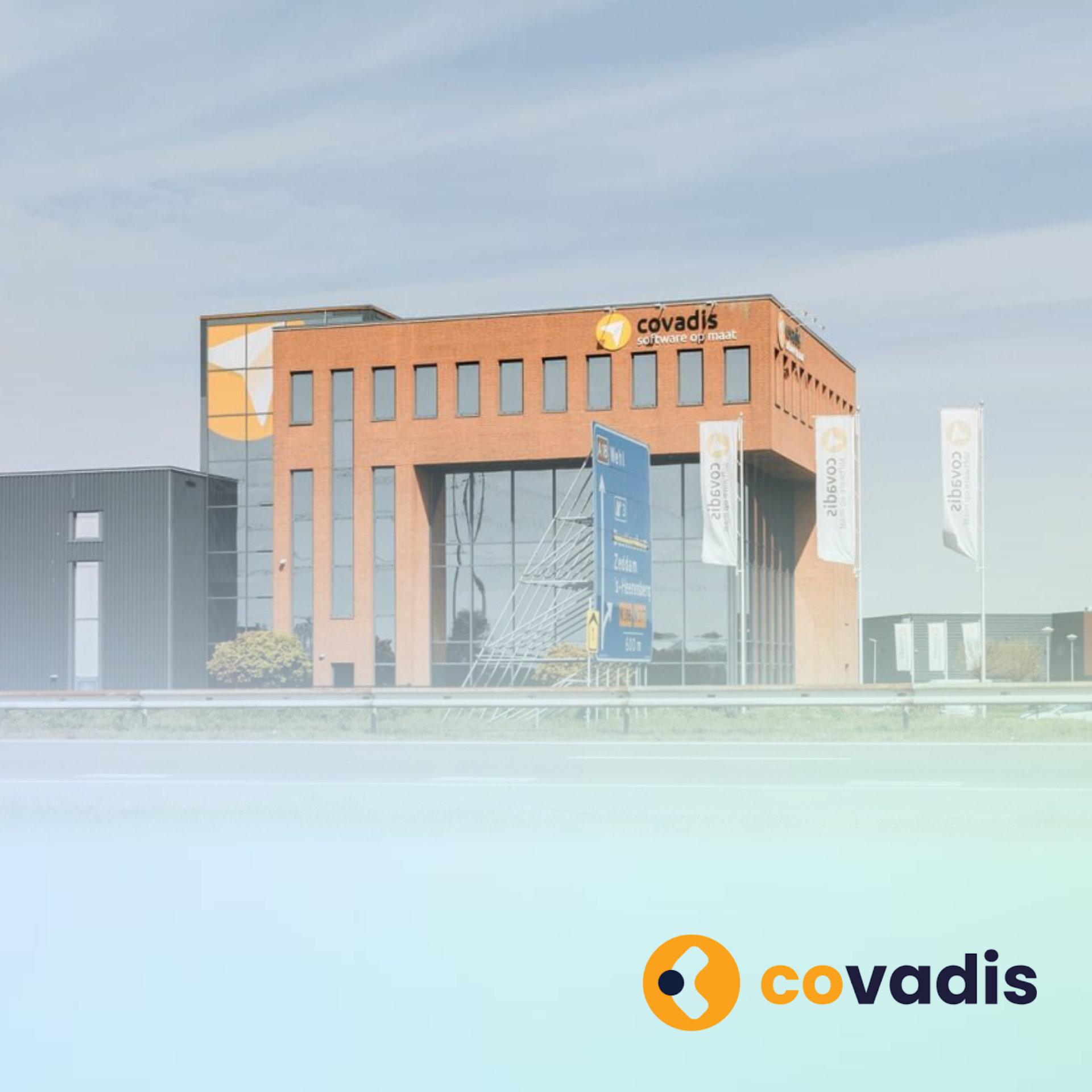 Het kantoorgebouw van Covadis met een oranje gevel onder een bewolkte hemel, het logo zichtbaar op de voorgrond.