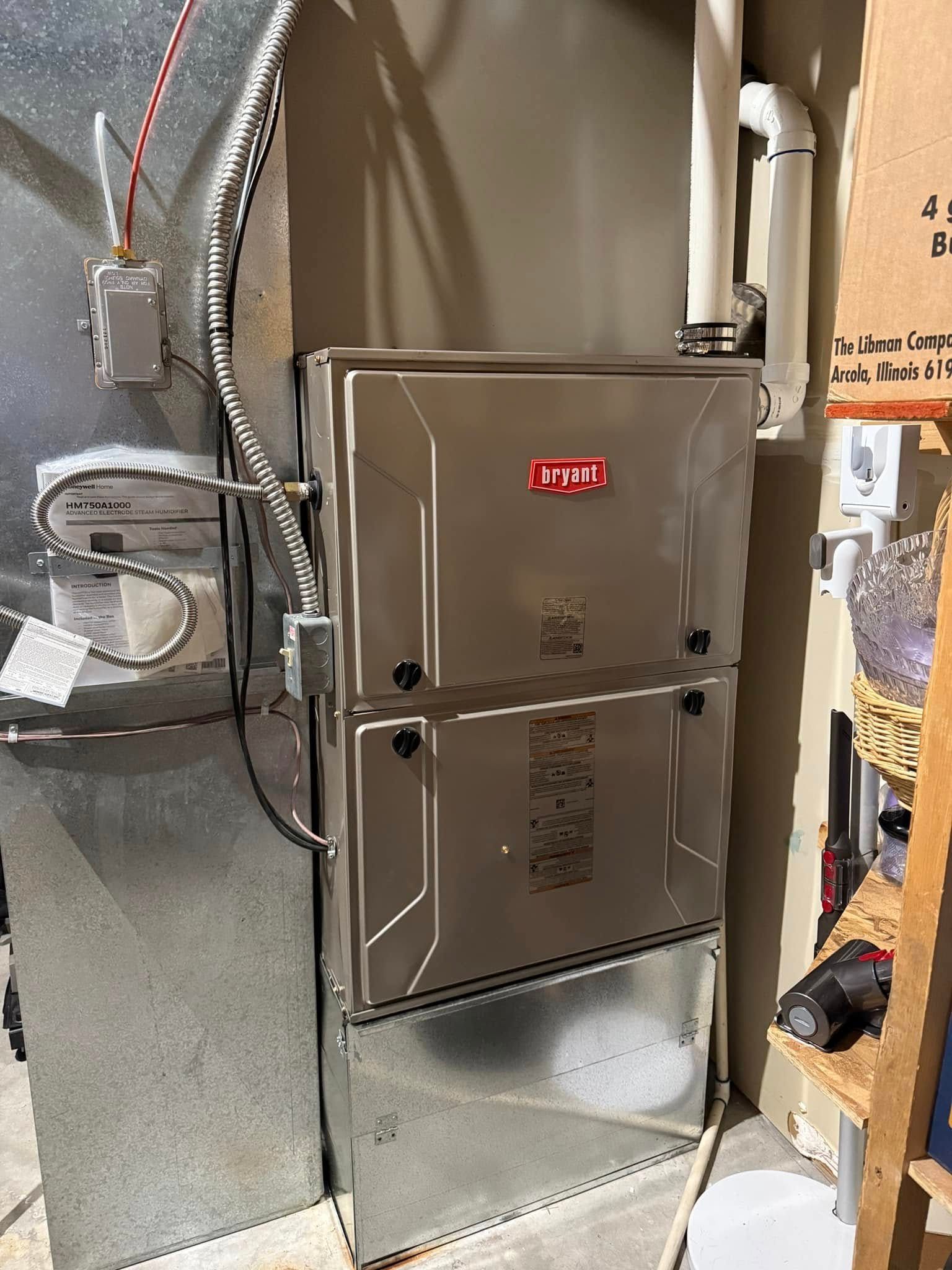 Gray HVAC furnace and ductwork in a utility closet with exposed pipes and cables.