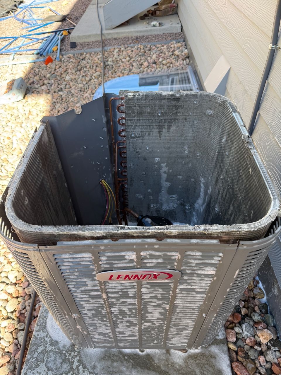 Open outdoor HVAC unit with missing top panel and visible debris inside