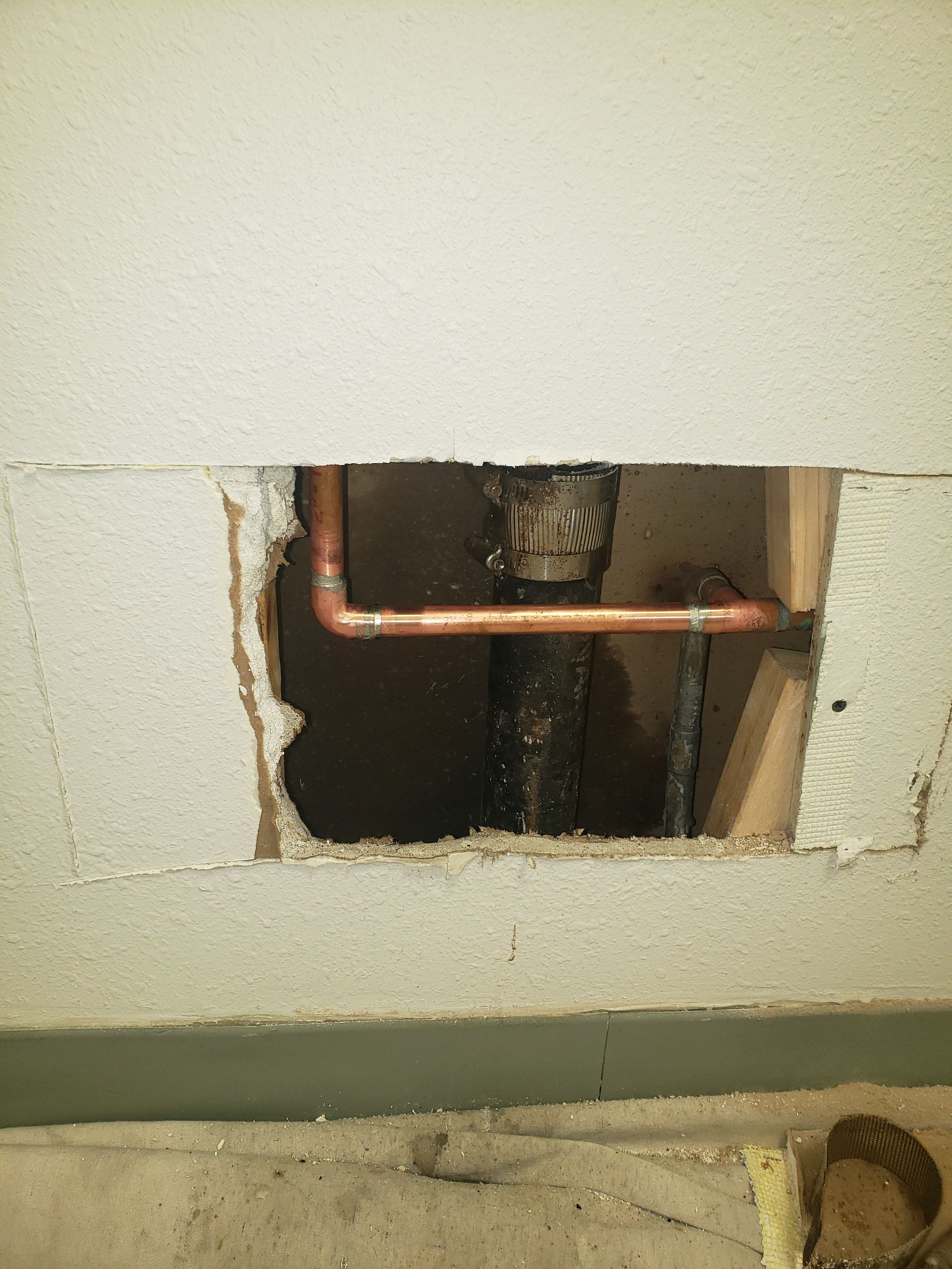 A hole in a wall with a pipe coming out of it.