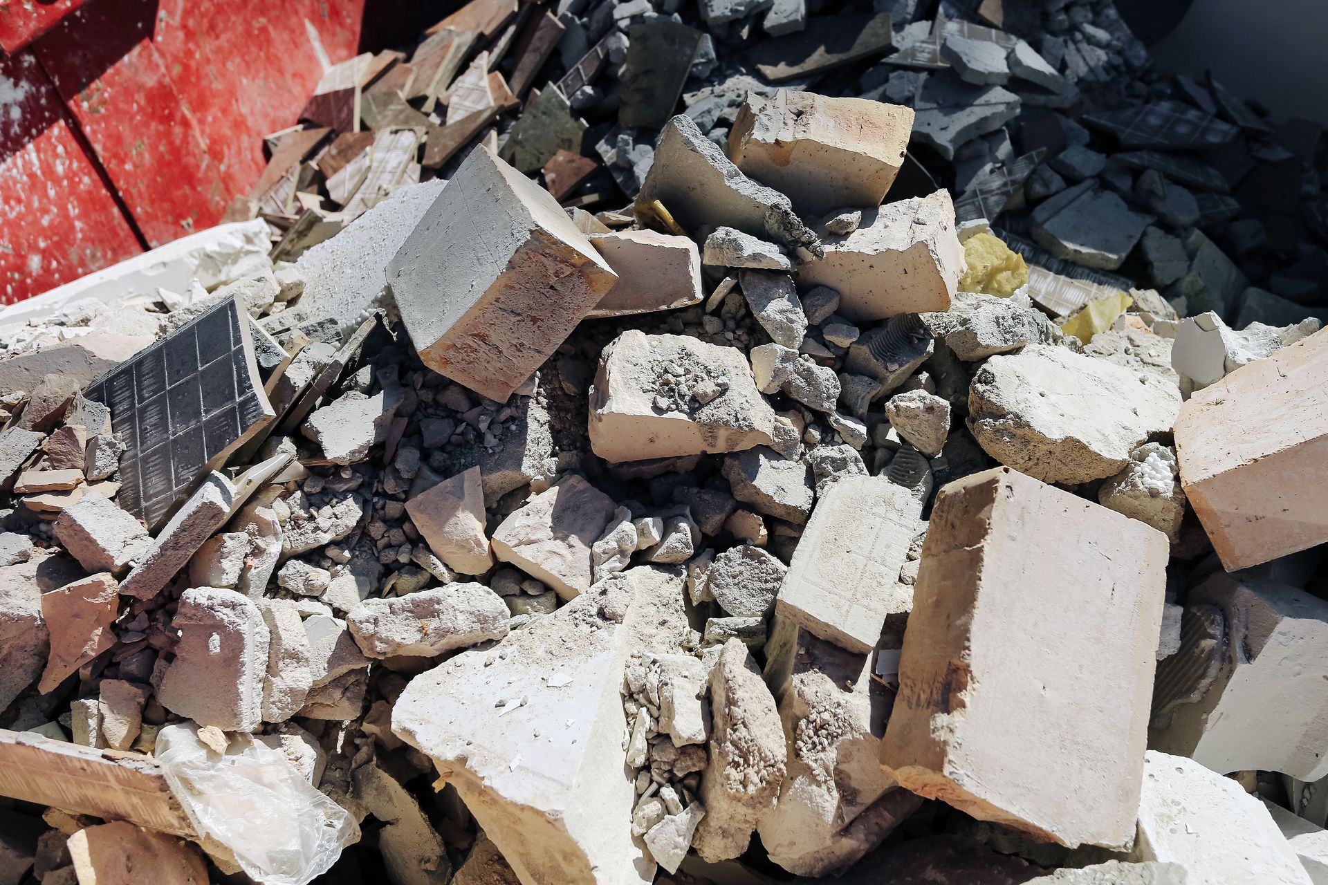 Pile of broken concrete, bricks, and debris in construction waste container.