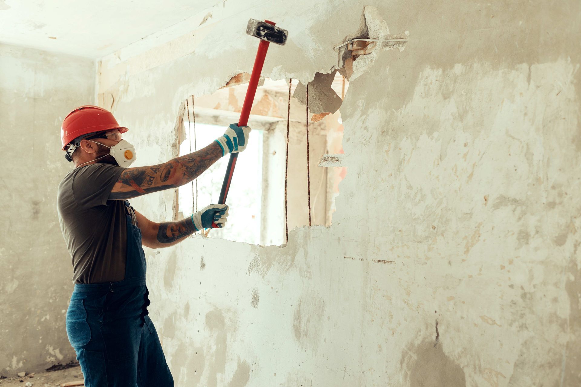 Builder with a hammer in his hands breaks the cement wall. Builder with a hammer in his hands breaks the cement wall.