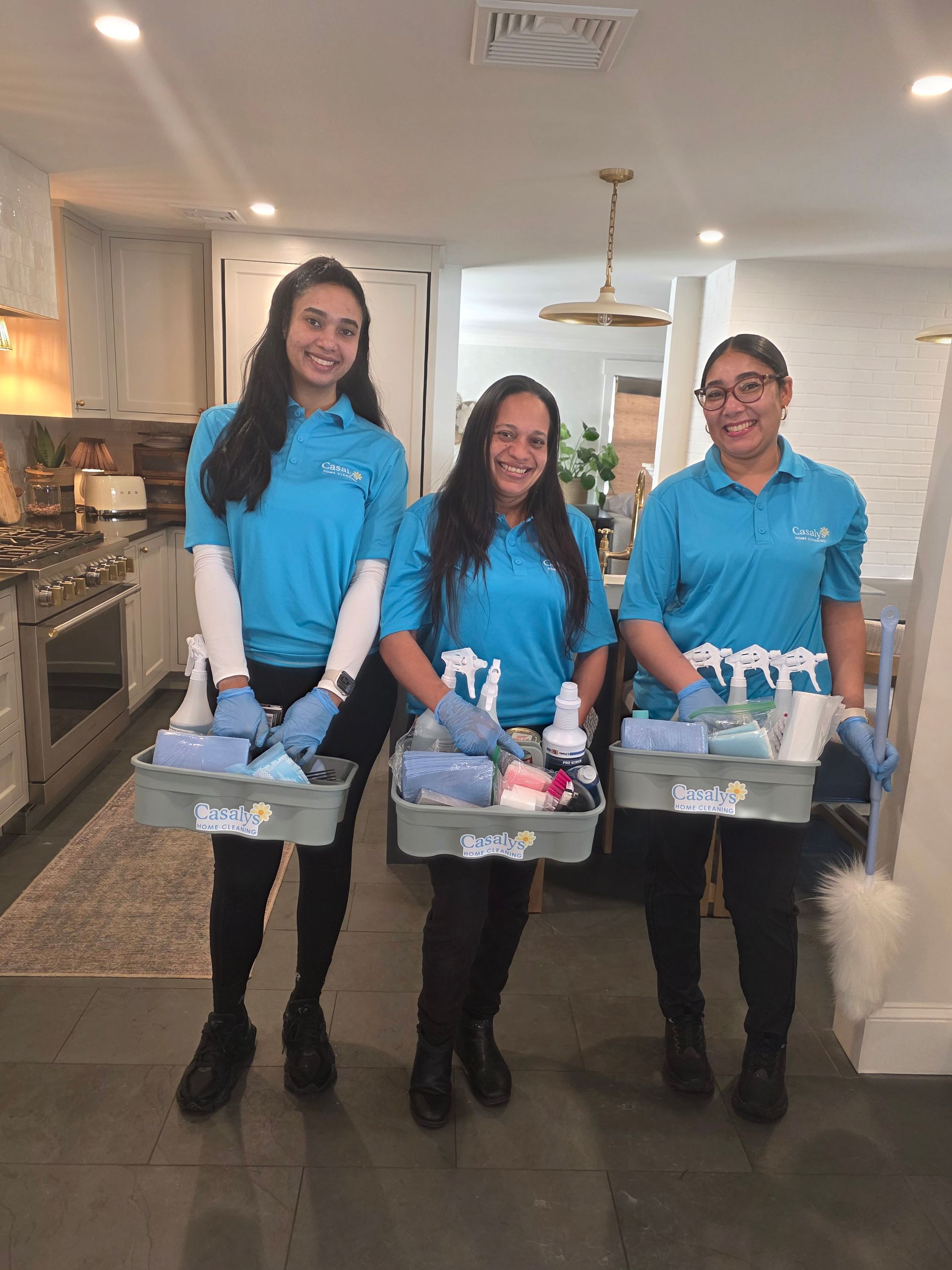 Three people in blue shirts hold donation bins in a bright hallway.