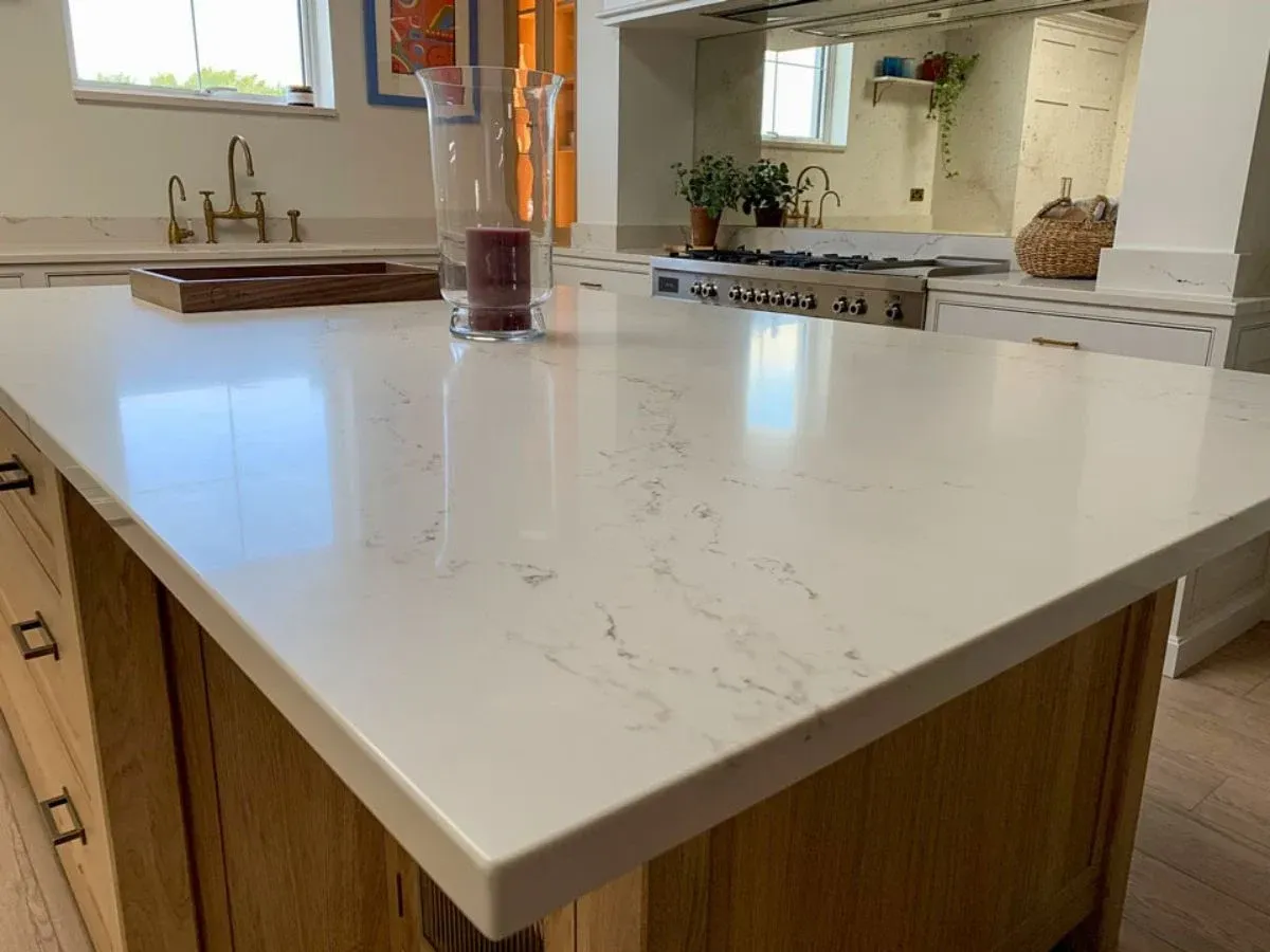 Bright kitchen with white cabinets, gray island countertop, stainless dishwasher, and a window over the sink.
