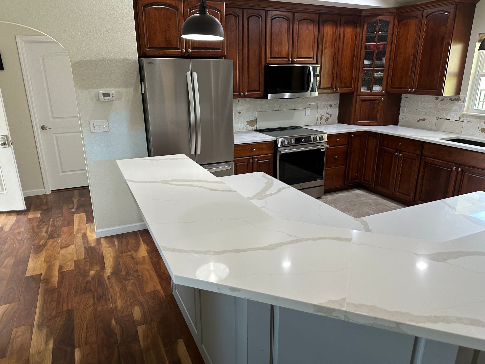 Granite kitchen countertops with dark wood cabinets and stainless steel appliances in a corner layout