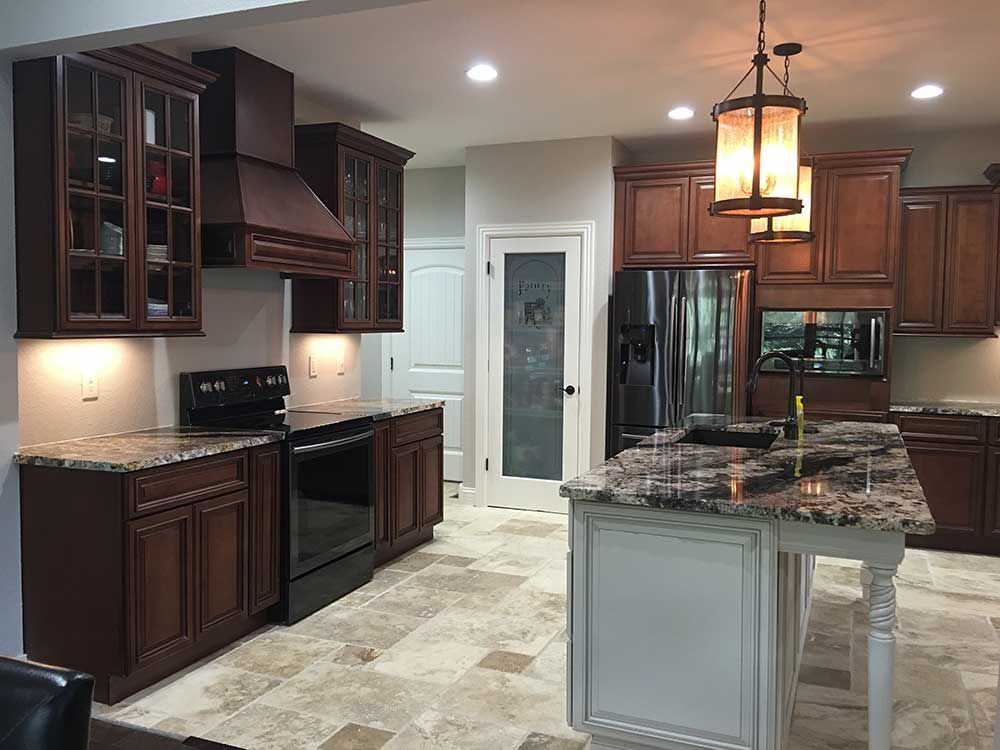 Modern kitchen with dark wood cabinets, granite island, stainless appliances, and tiled floor