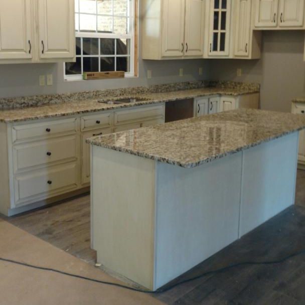 Bright kitchen with white cabinets, granite countertops, and a large island under installation