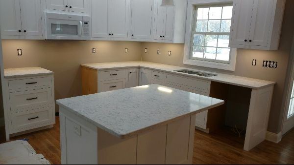 Bright white kitchen with island, white cabinets, beige backsplash, wood floor, and a window above the counter.