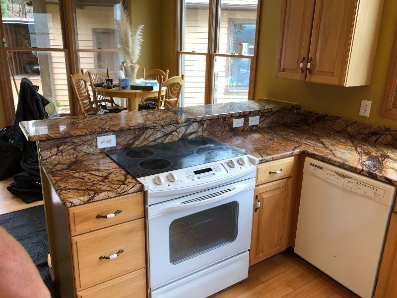 Kitchen with granite countertops, white stove and dishwasher, and a sink overlooking a dining area.