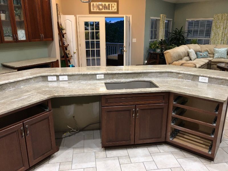 Curved kitchen counter with dark wood cabinets and beige tile in a warm-toned home kitchen
