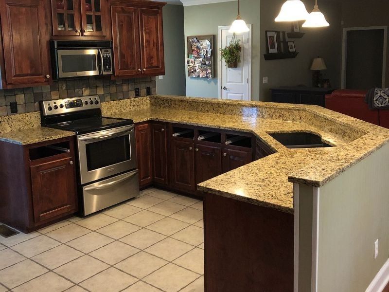 Kitchen with stainless steel stove, dark wood cabinets, and a granite breakfast bar countertop.