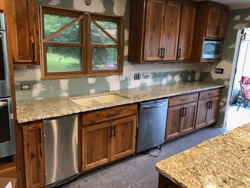 Kitchen with wooden cabinets, granite countertops, window over sink, and dishwasher under the counter.