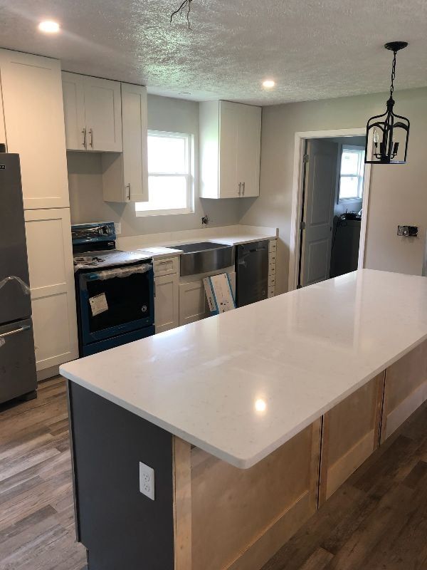 Bright kitchen with white cabinets, stainless appliances, and a large white island.