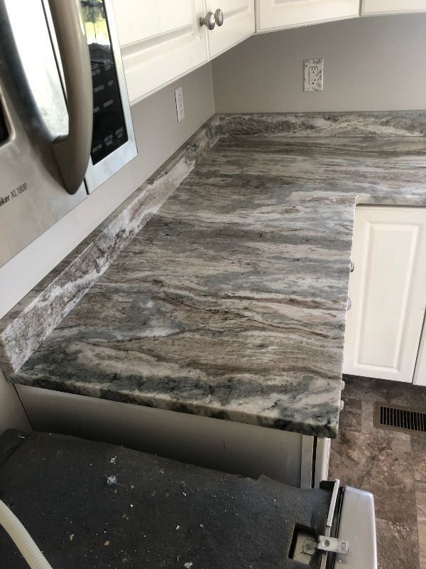 Kitchen countertop with gray veined stone and a built-in microwave on the left