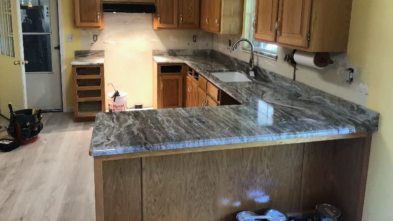 Kitchen with wooden cabinets, granite island, and stainless sink in a bright, empty home interior