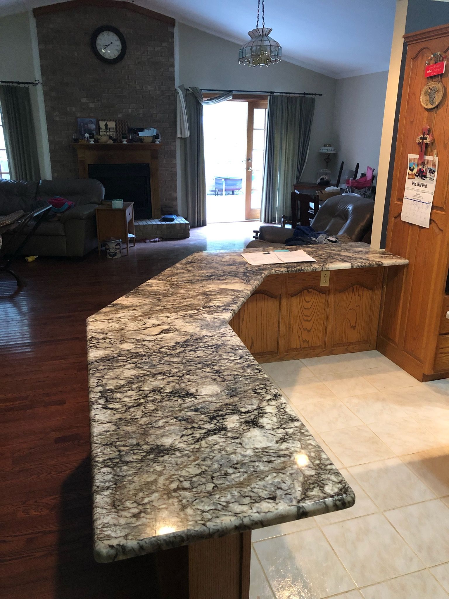 Kitchen with dark granite island countertop opening to a living room and patio doors in the background