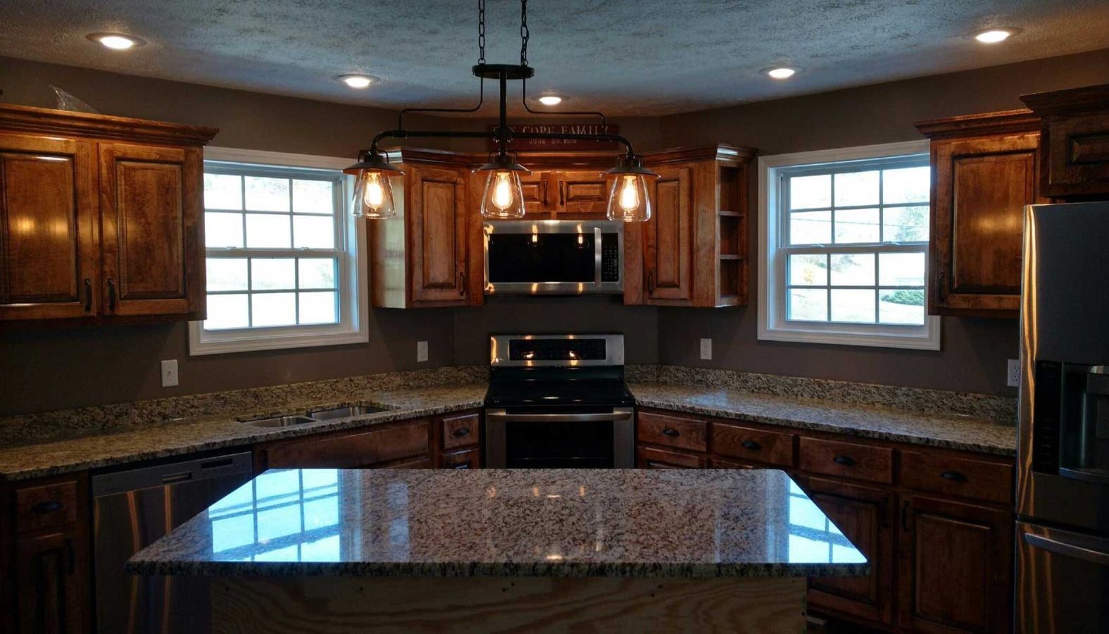 Spacious kitchen with dark wood cabinets, granite counters, and stainless steel appliances under recessed lighting