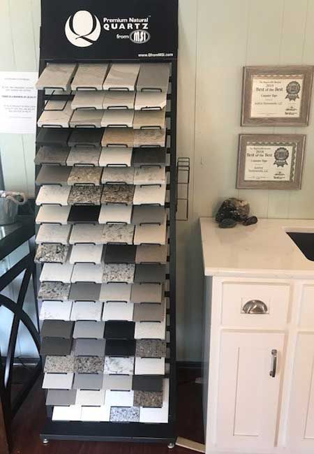 Wall-mounted brochure rack with brochures, framed certificates, and a white cabinet in an office lobby