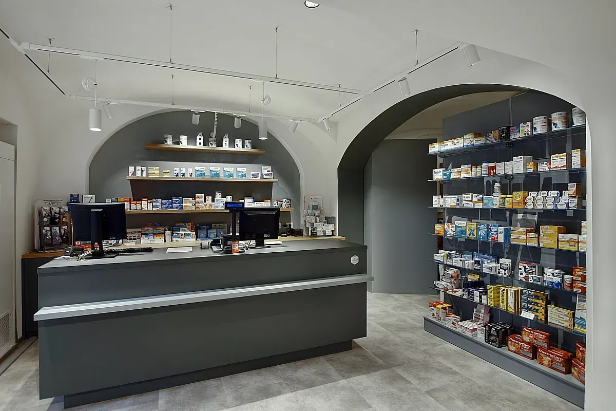 Arredamento Farmacia Ferrero Novara, banco cassa, expo a parete con pedana e ripiani in vetro