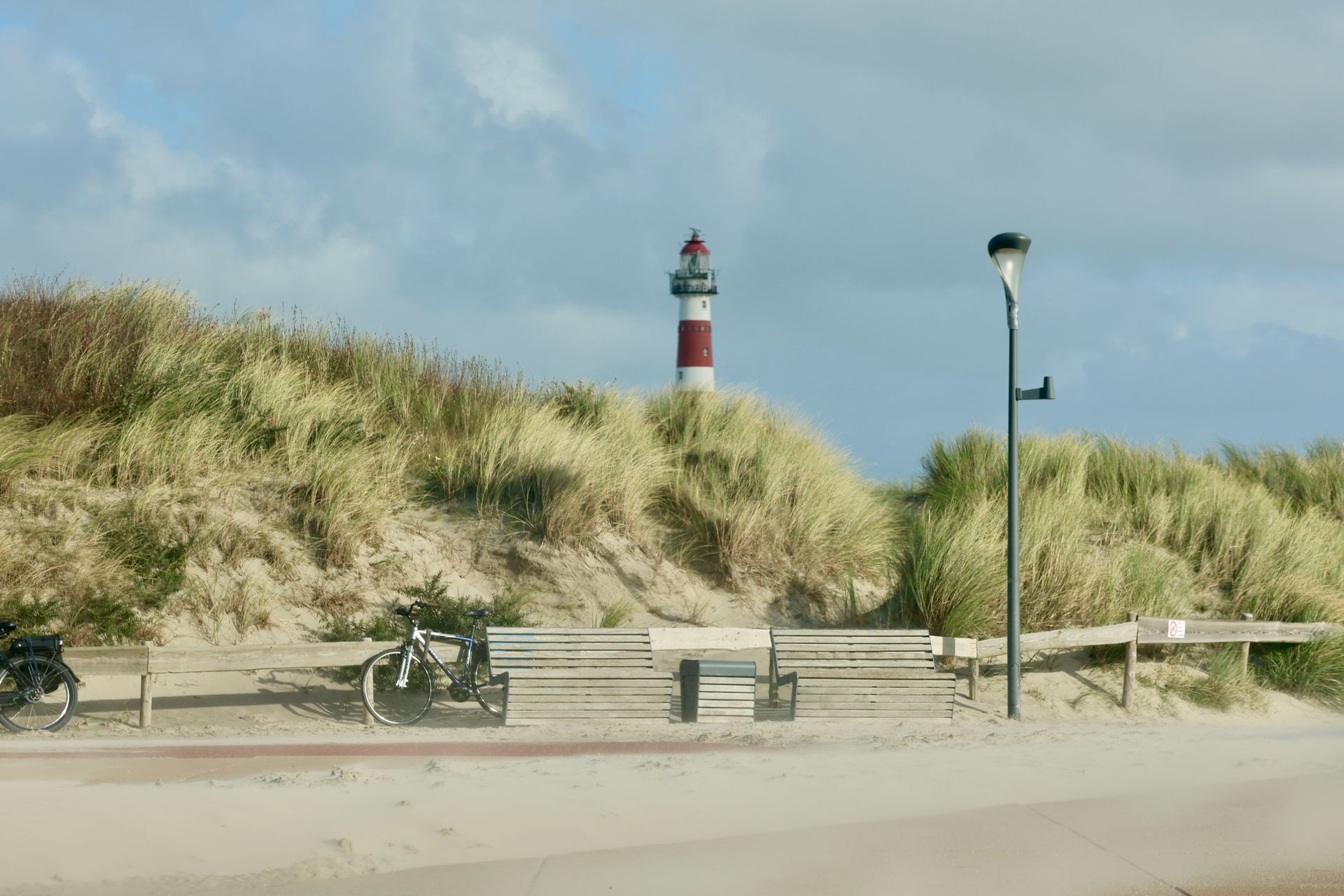 A red and white lighthouse is sitting on top of a sand dune, Ameland.