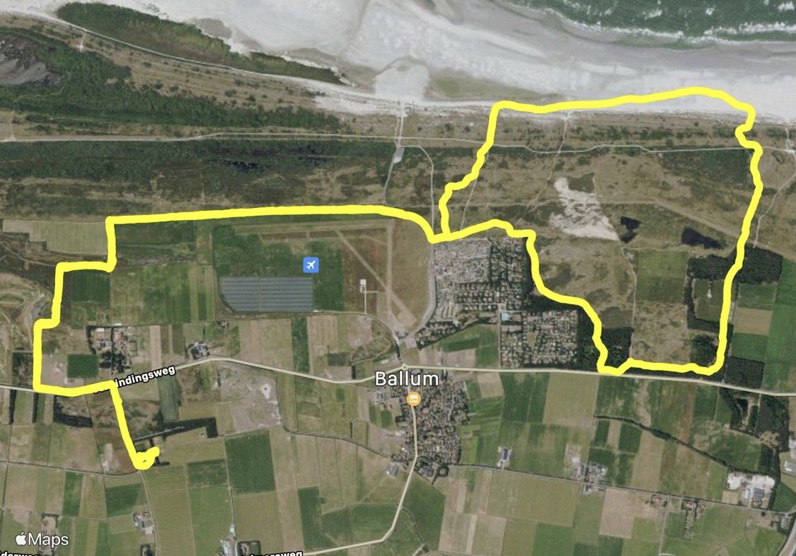 Luchtfoto van het kustgebied, aangegeven met een gele lijn, met daarop het strand, velden, gebouwen en wegen.