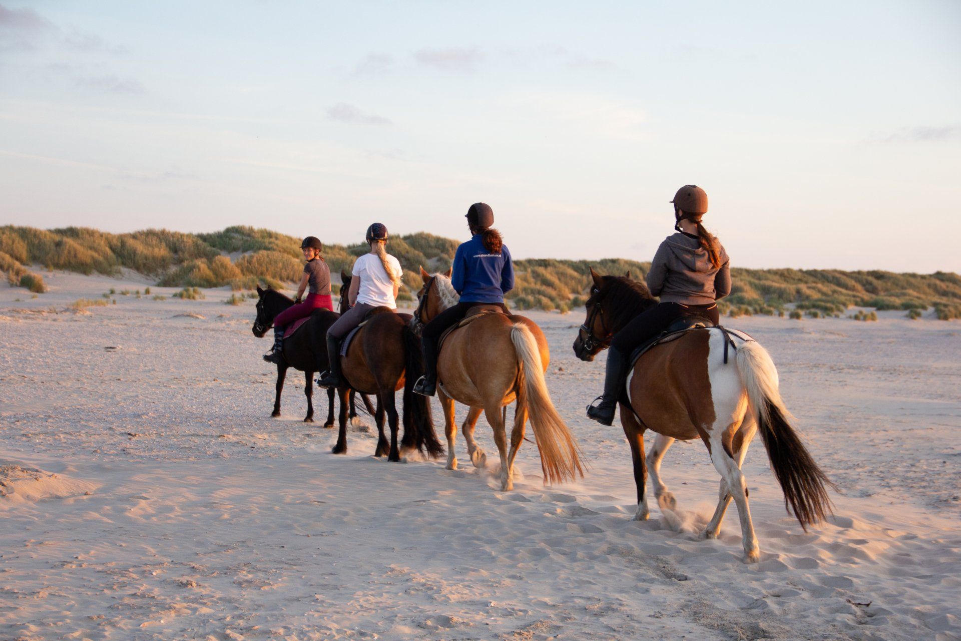Gevorderde ruiters rijden onder begeleiding van ervaren gids via de duinen terug naar huis.