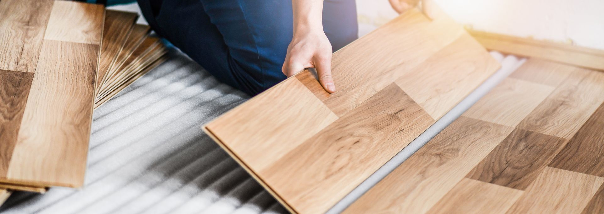 A person is installing a wooden floor in a room.