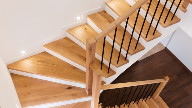 A wooden staircase with a black railing in a house.
