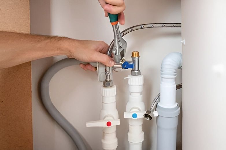 A Person Using Pliers on Plumbing Pipes in a Cabinet — David Lewis Solahart in Bangalow, NSW