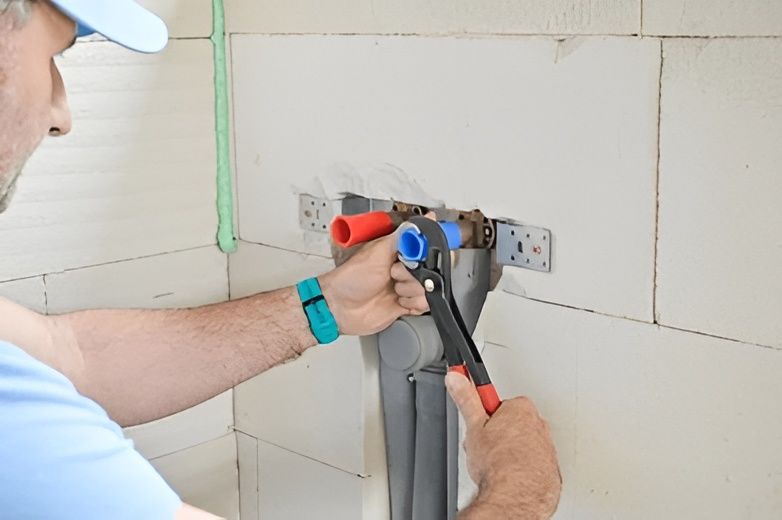 A Plumber Using a Wrench on Water Pipes Inside a Building — David Lewis Solahart in Ballina, NSW